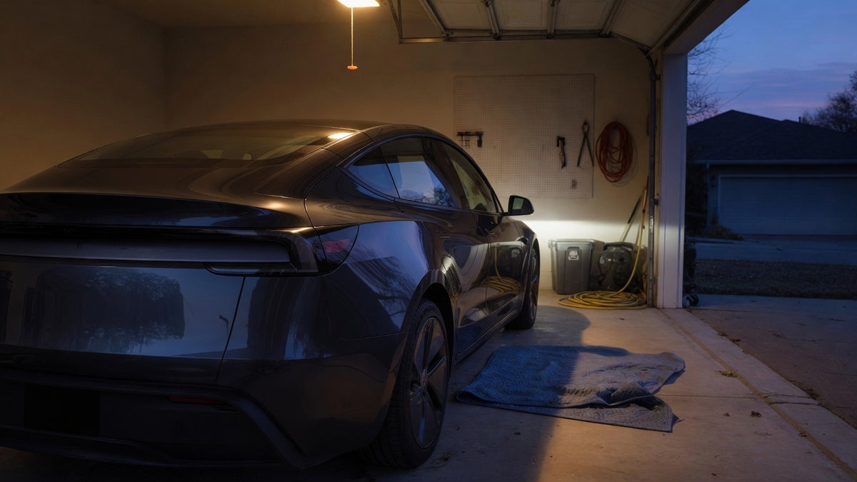 A dark electric sedan on its first night home in a garage