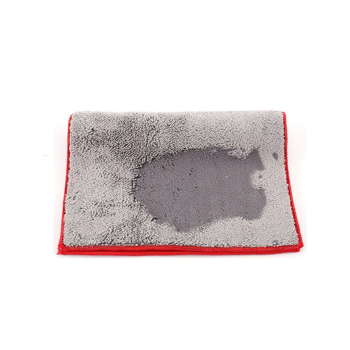 Grey plush face of a red-edged dual-sided microfiber car towel with moisture on the fabric